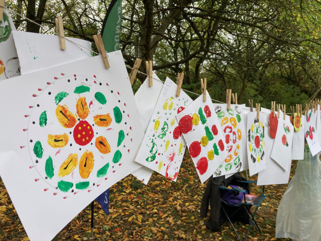 A collection of children's artwork pegged up on a line to dry and display.