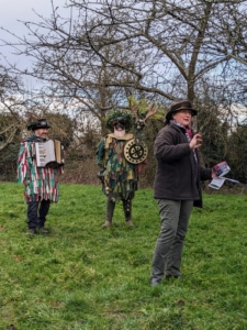 The leader of the Golden Wassail explaining the event with characters dressed in traditional costumes.